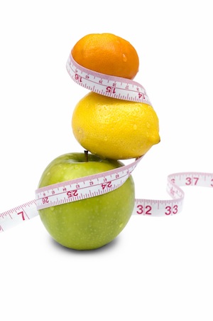 Weight loss and healthy dieting concept. Apple, lemon and mandarin with measure tape. Isolated over white.