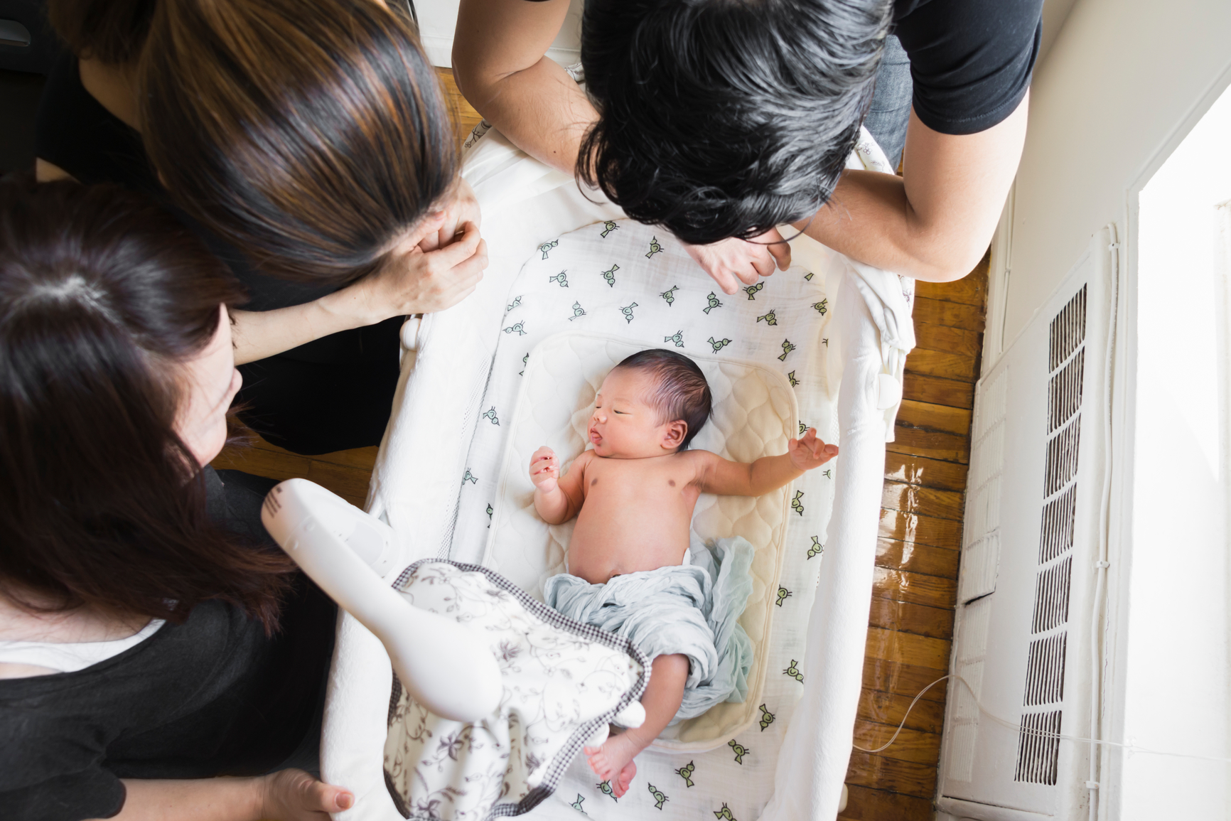 An 8-day old Japanese newborn baby with his parents and grandmother