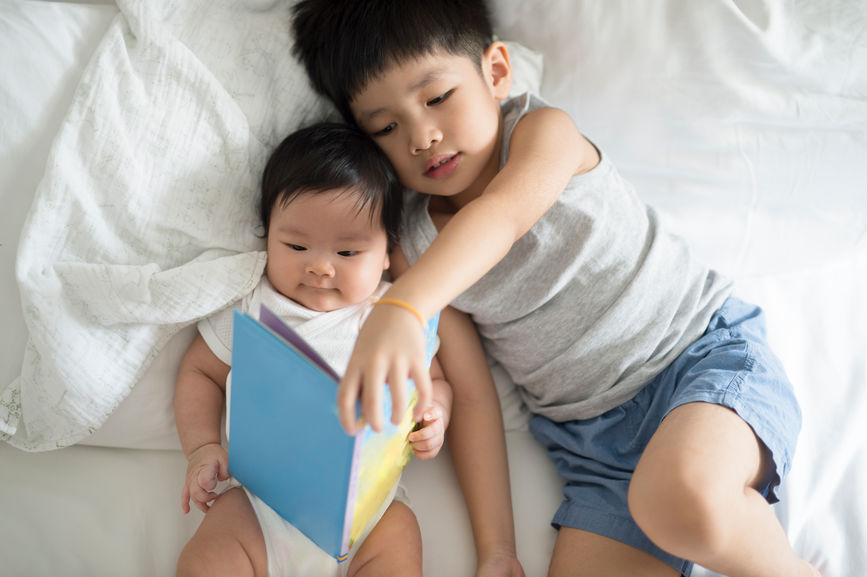 Siblings Reading On A Bed